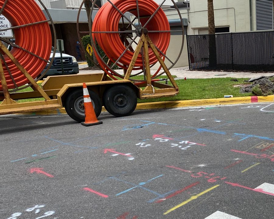 Orange conduit reels on a trailer beside a locate-marked crossing